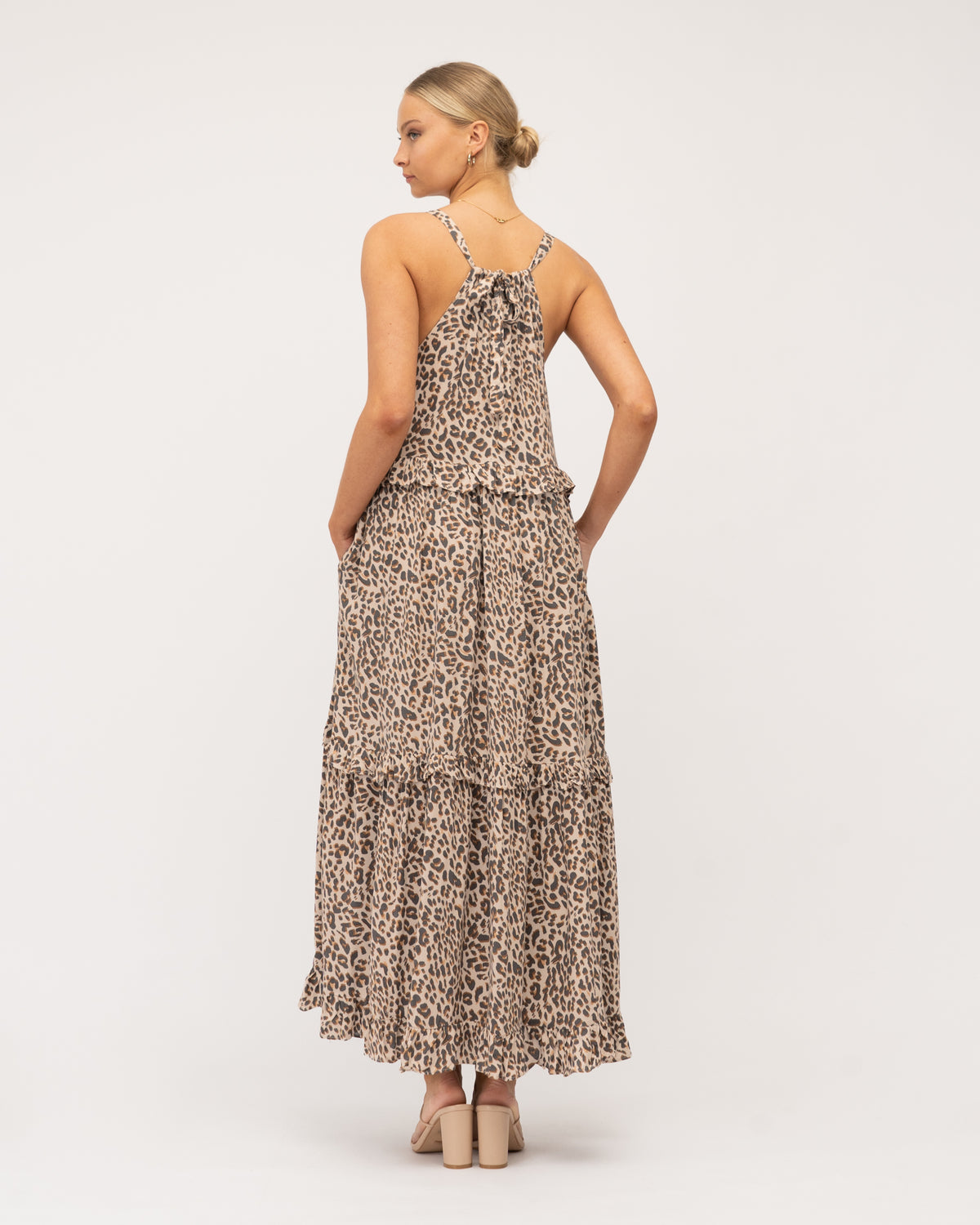 A model wearing Global Fashion House maxi tiered dress featuring animal print, shirring detail at the neckline, adjustable straps that tie at the back.