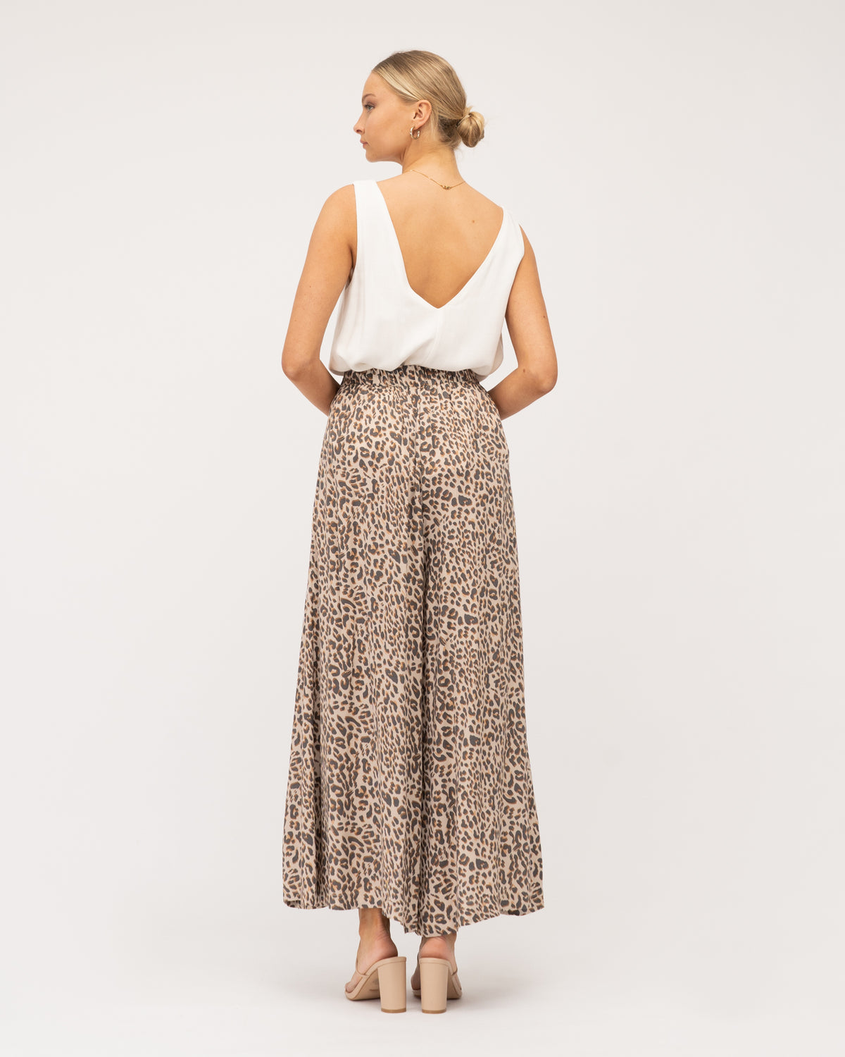 A model wearing animal print wide-leg pants featuring a flat front waistband, an elastic back waistband, and a wide leg design curated by Global Fashion House.