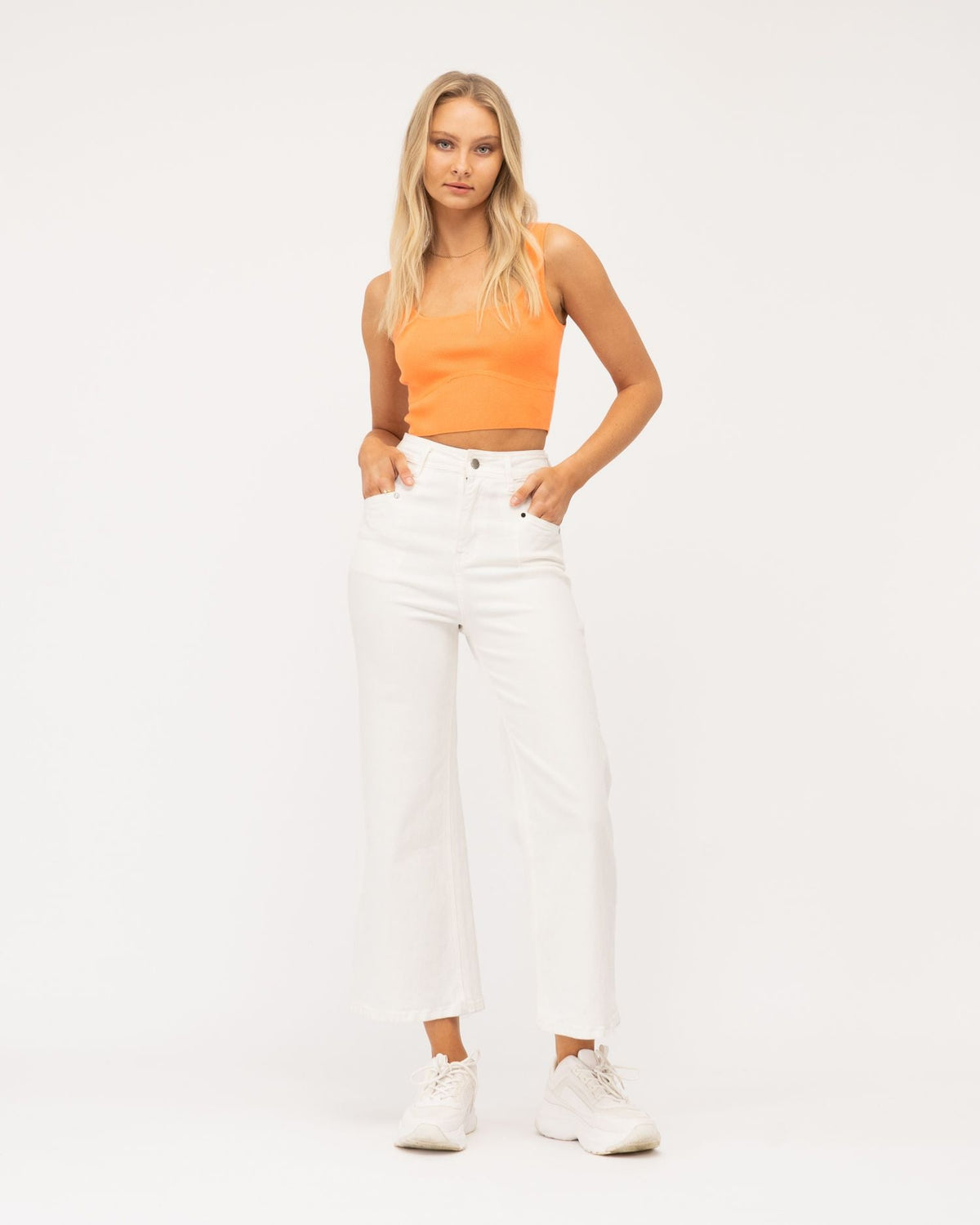 A girl wearing orange top and white cropped wide leg jeans from Paper Heart collection designed by Global Fashion House.