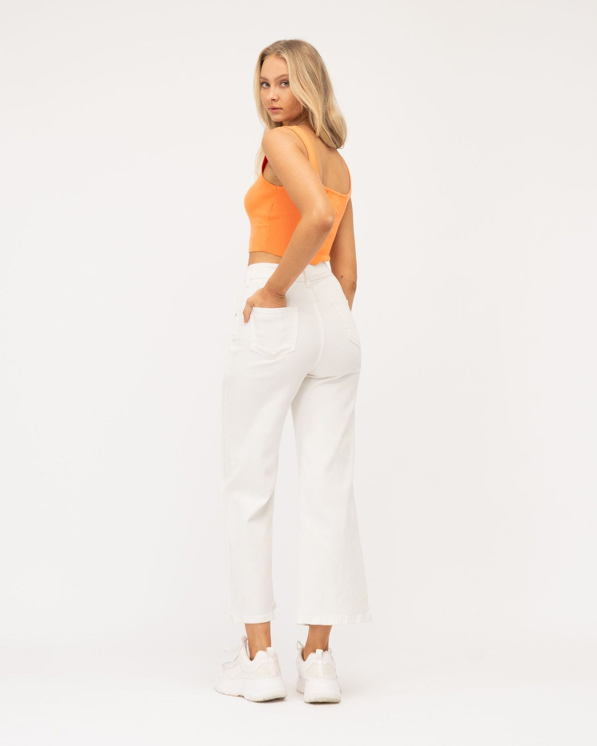 A girl wearing orange top and white cropped wide leg jeans from Paper Heart collection designed by Global Fashion House.