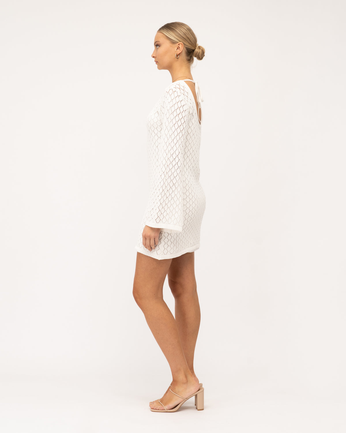 A model wearing white long sleeve crochet mini dress with loose sleeves and round neckline from Paper Heart collection designed by Global Fashion House.