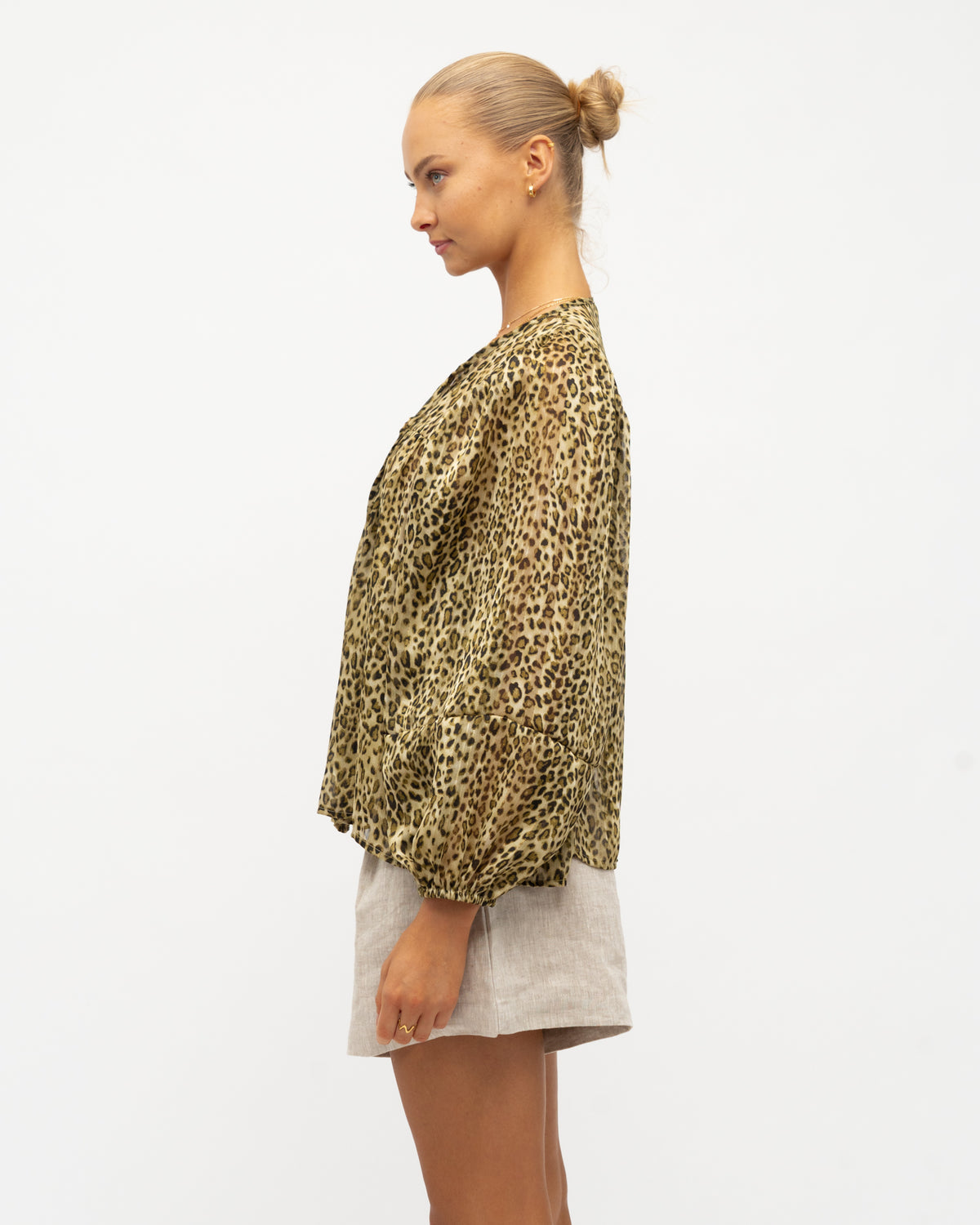 A model wearing an animal print blouse with a tie neckline, blouson sleeves, and elasticated cuffs from the White Closet collection designed by Global Fashion House.